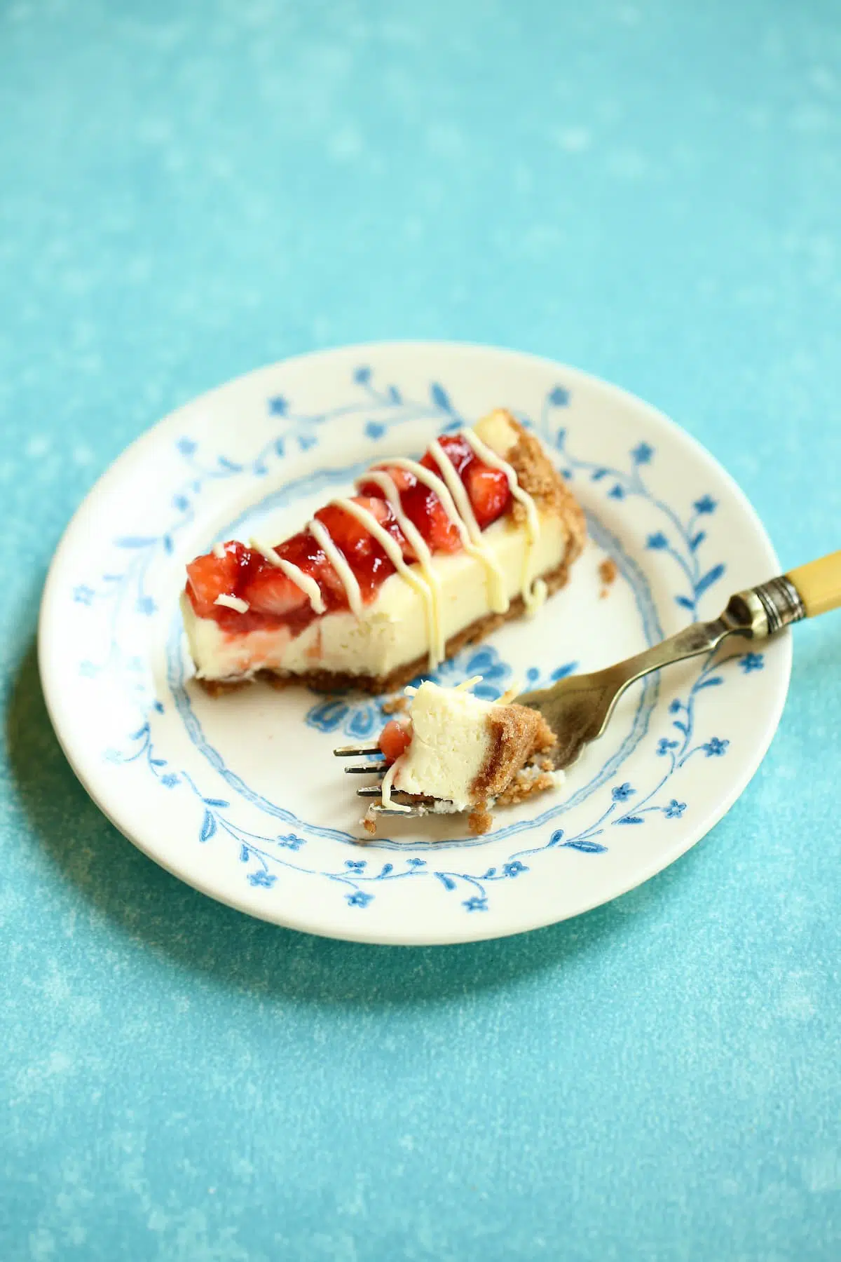 a blue and white plate with cheesecake bars on it and a fork with a bite out if it.