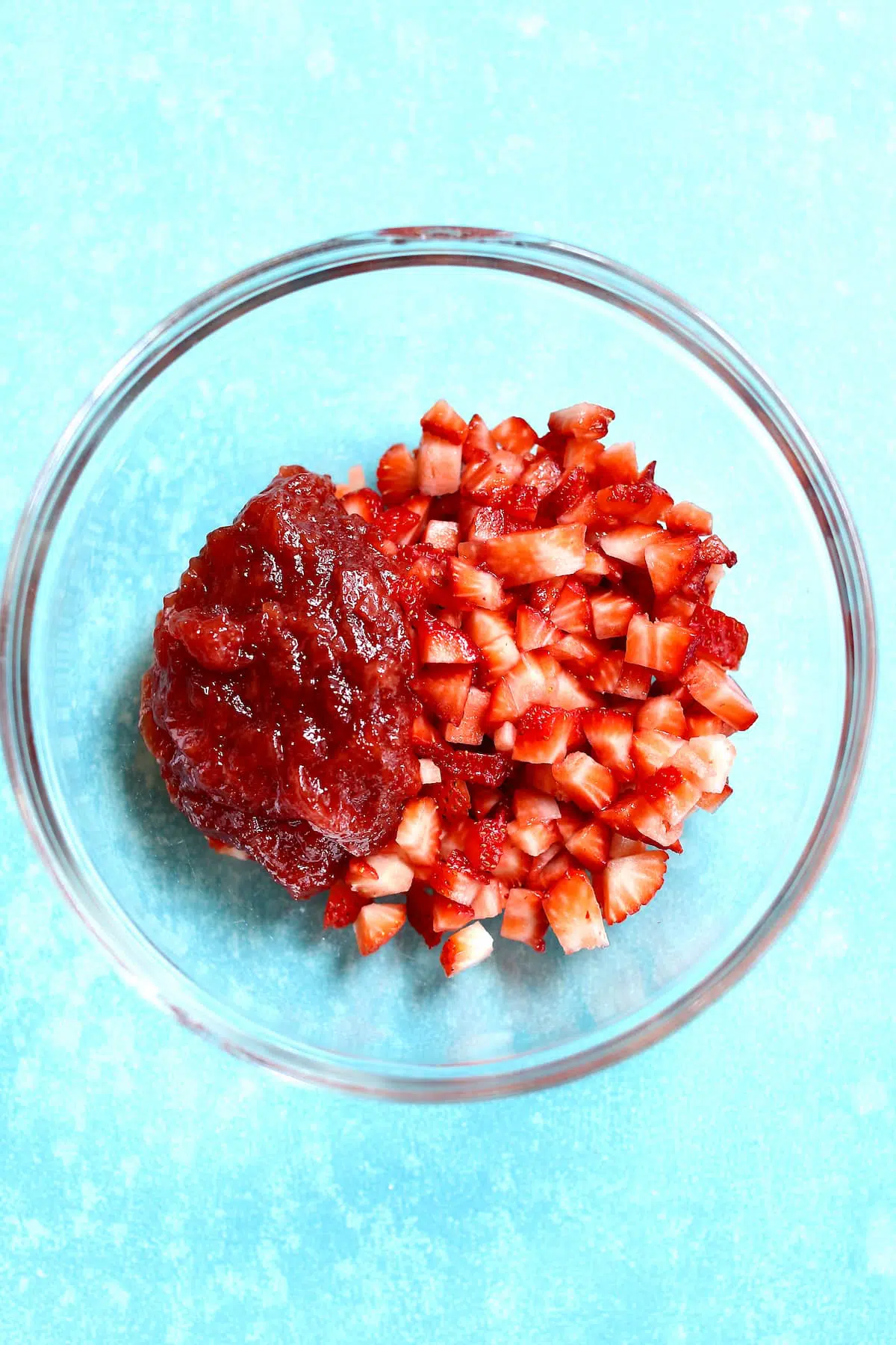 a bowl of diced fresh strawberries and a scoop of strawberry jam.