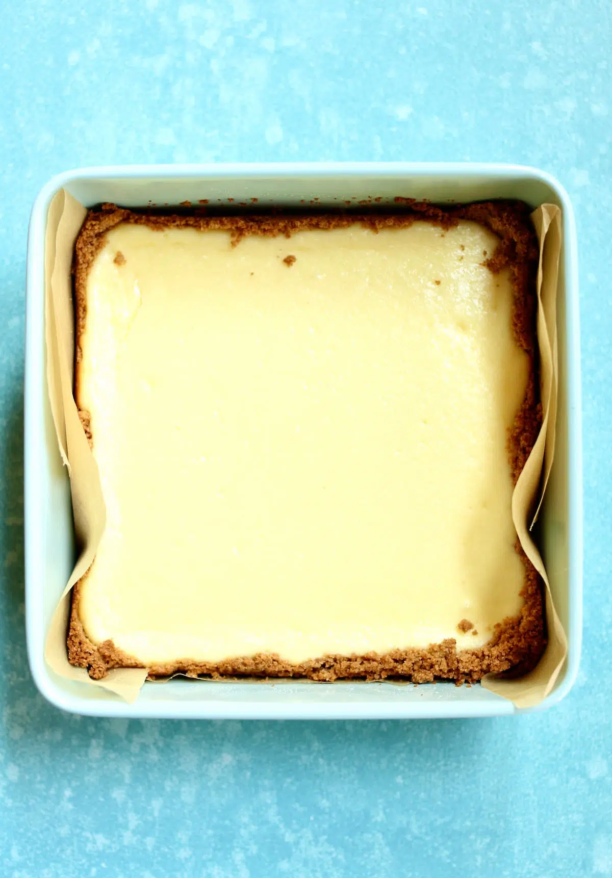 a square baking pan with cheesecake in it.
