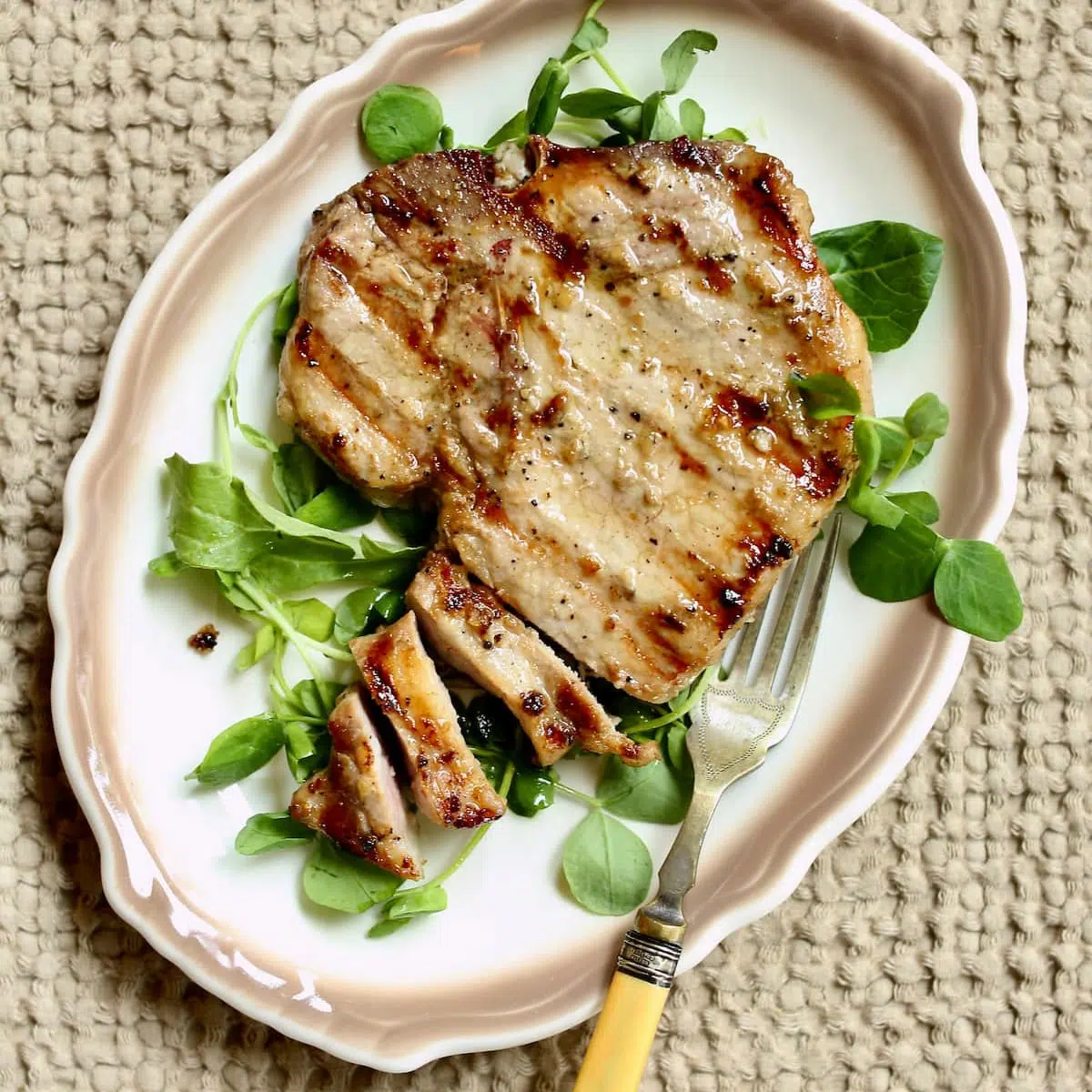 a pork chop of a white and brown plate.