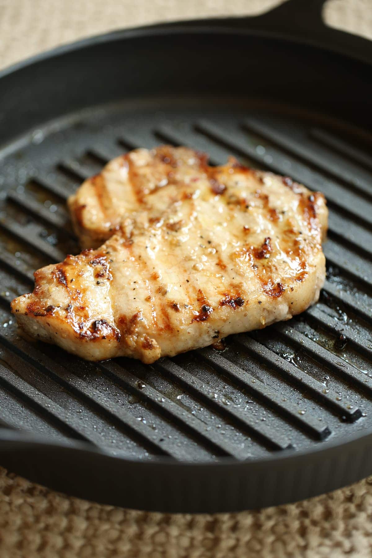 a side photo of a cooked pork chop in a grill pan.