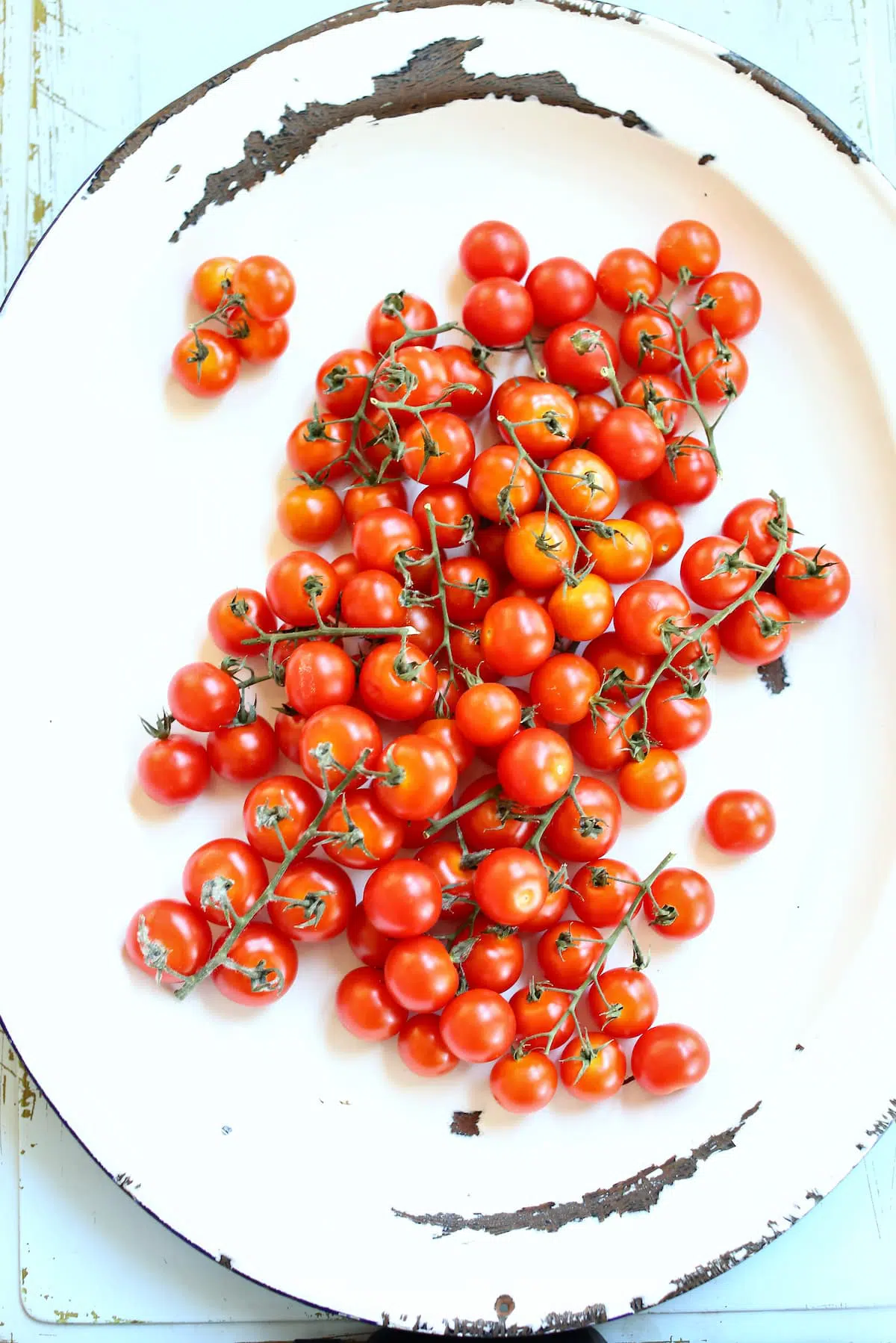 a white platter with cherry tomatoes on the top, scattered around.