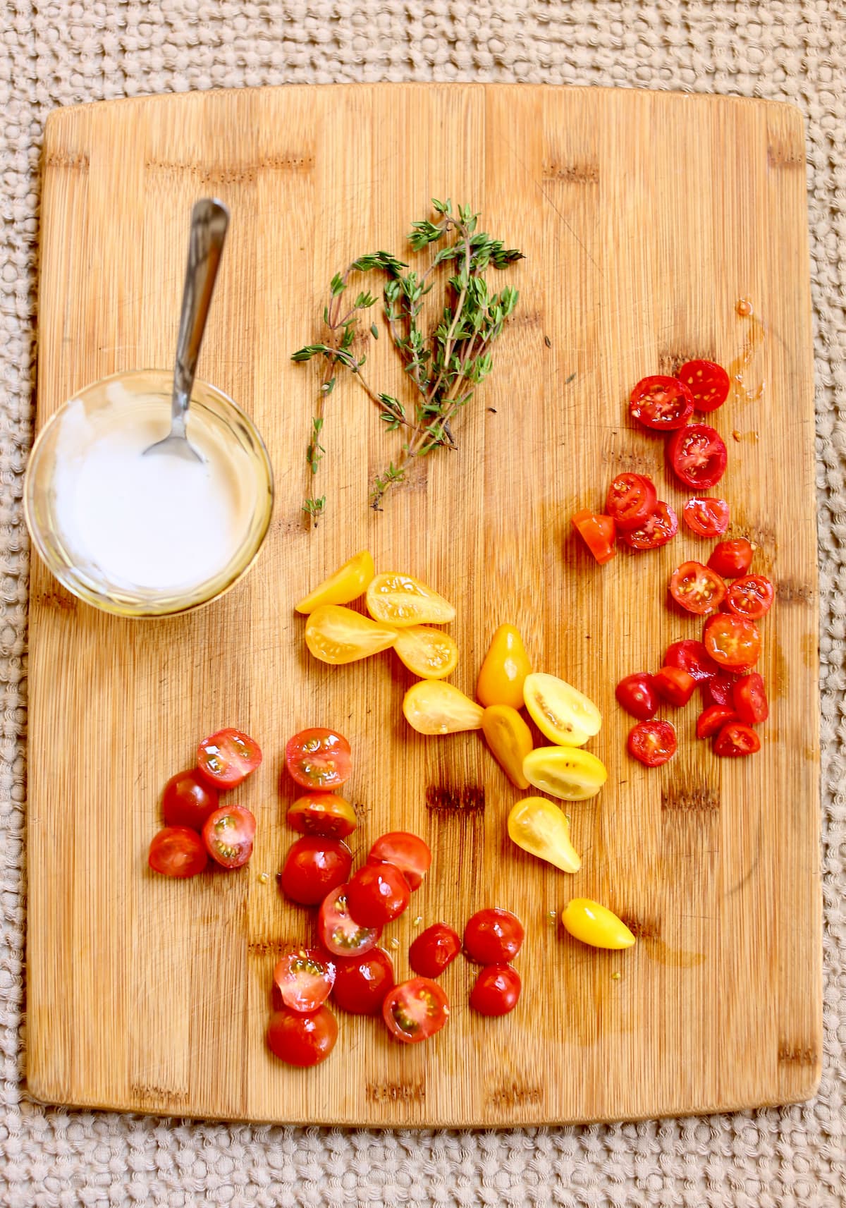 a cutting board with cut tomatoes and other ingredients for soup.