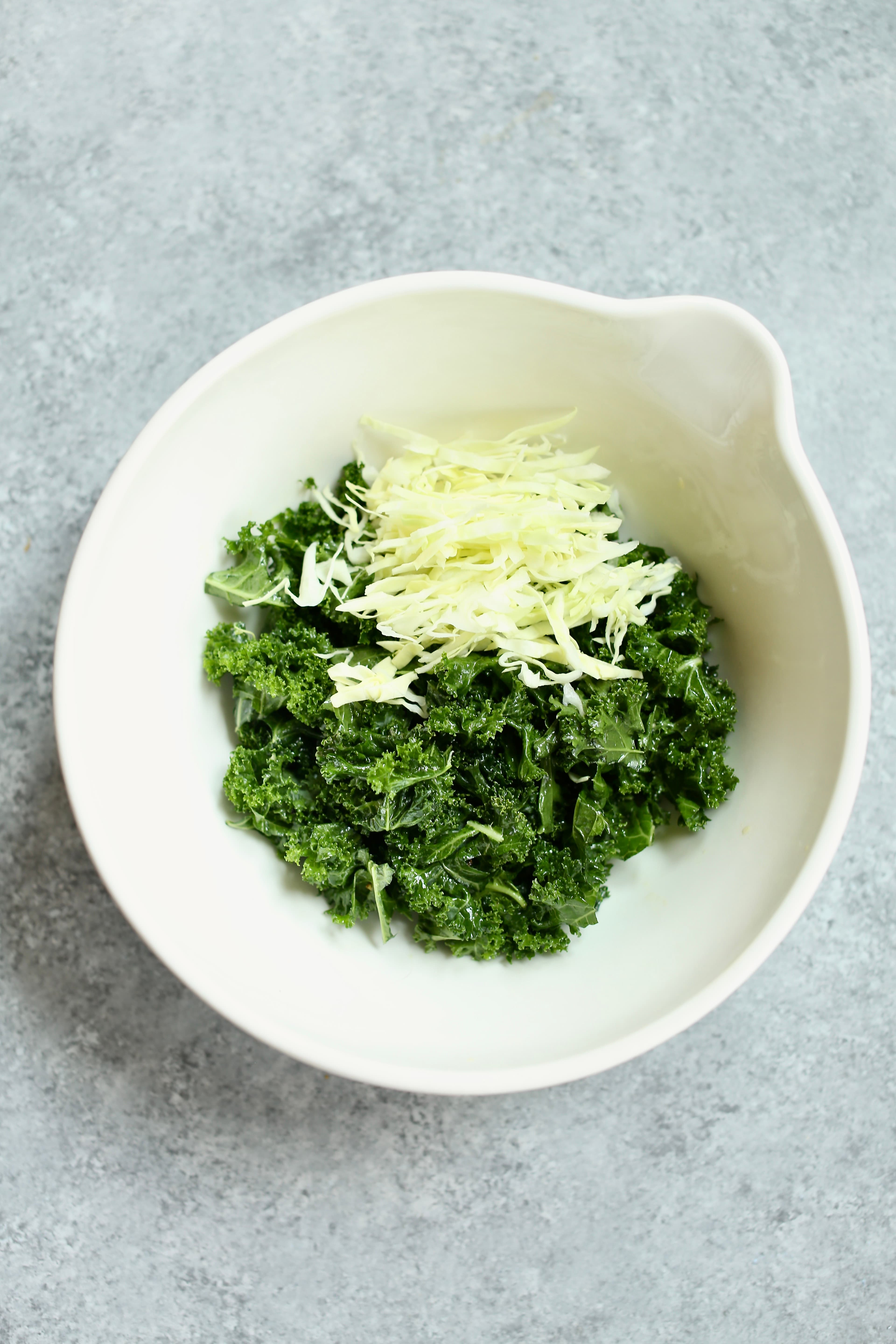 a white bowl of kale and cabbage.
