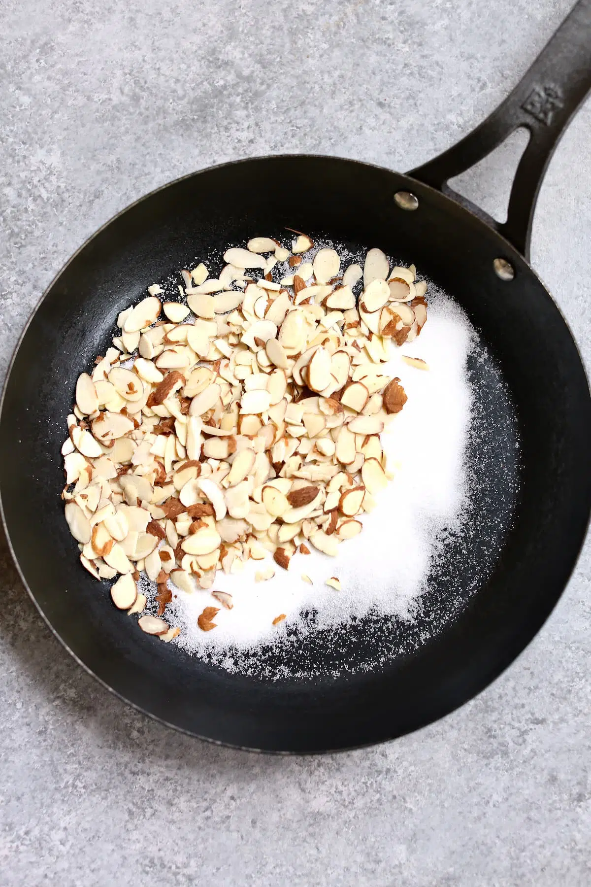 a black skillet with almonds and sugar in it.