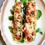 a plate with two stuffed zucchini on it and a text overlay saying the recipe name.