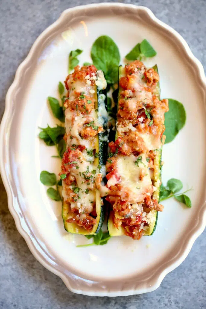 a plate with brown trim and two stuffed zucchini on it.