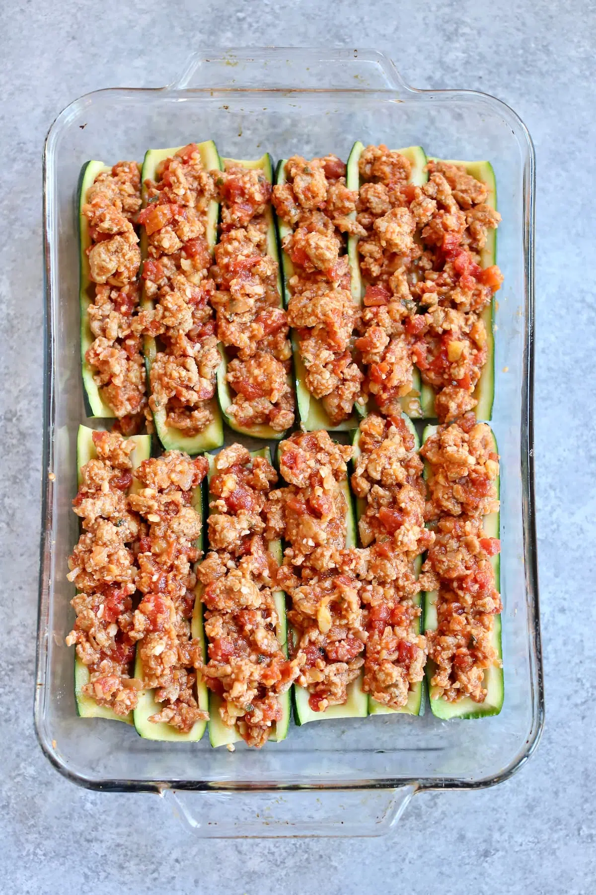 a tray of uncooked zucchini boats without cheese on them.
