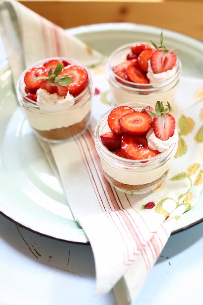 a table with three strawberry cheesecakes on it.