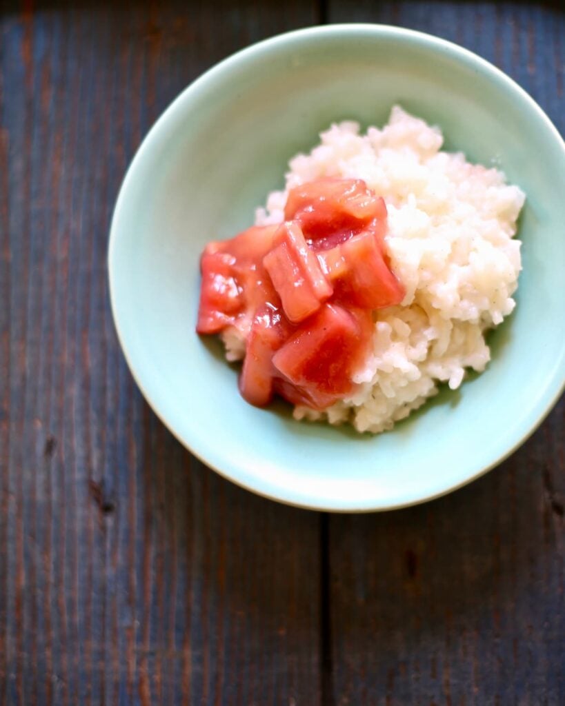 a blue bowl of rice pudding with rhubarb sauce.