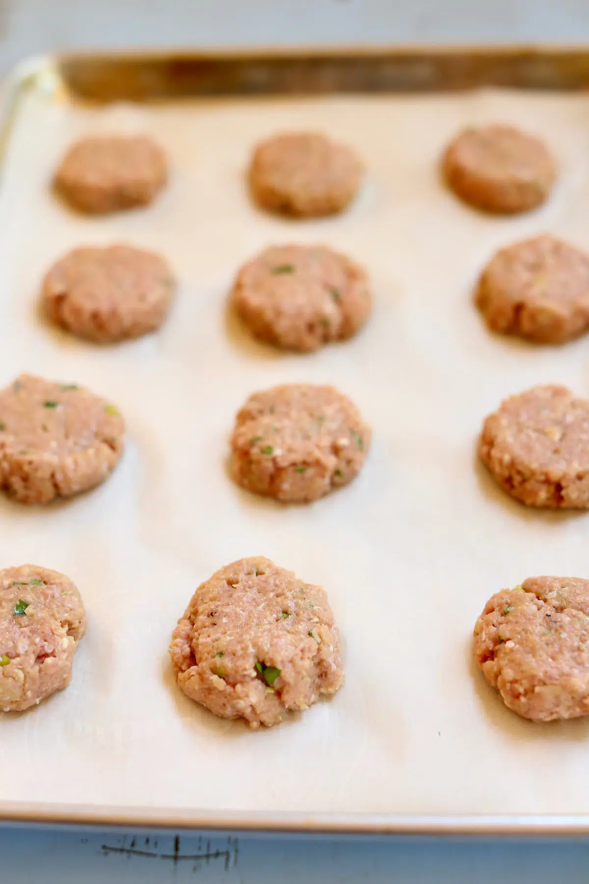 a sheet of uncooked turkey burger sliders.