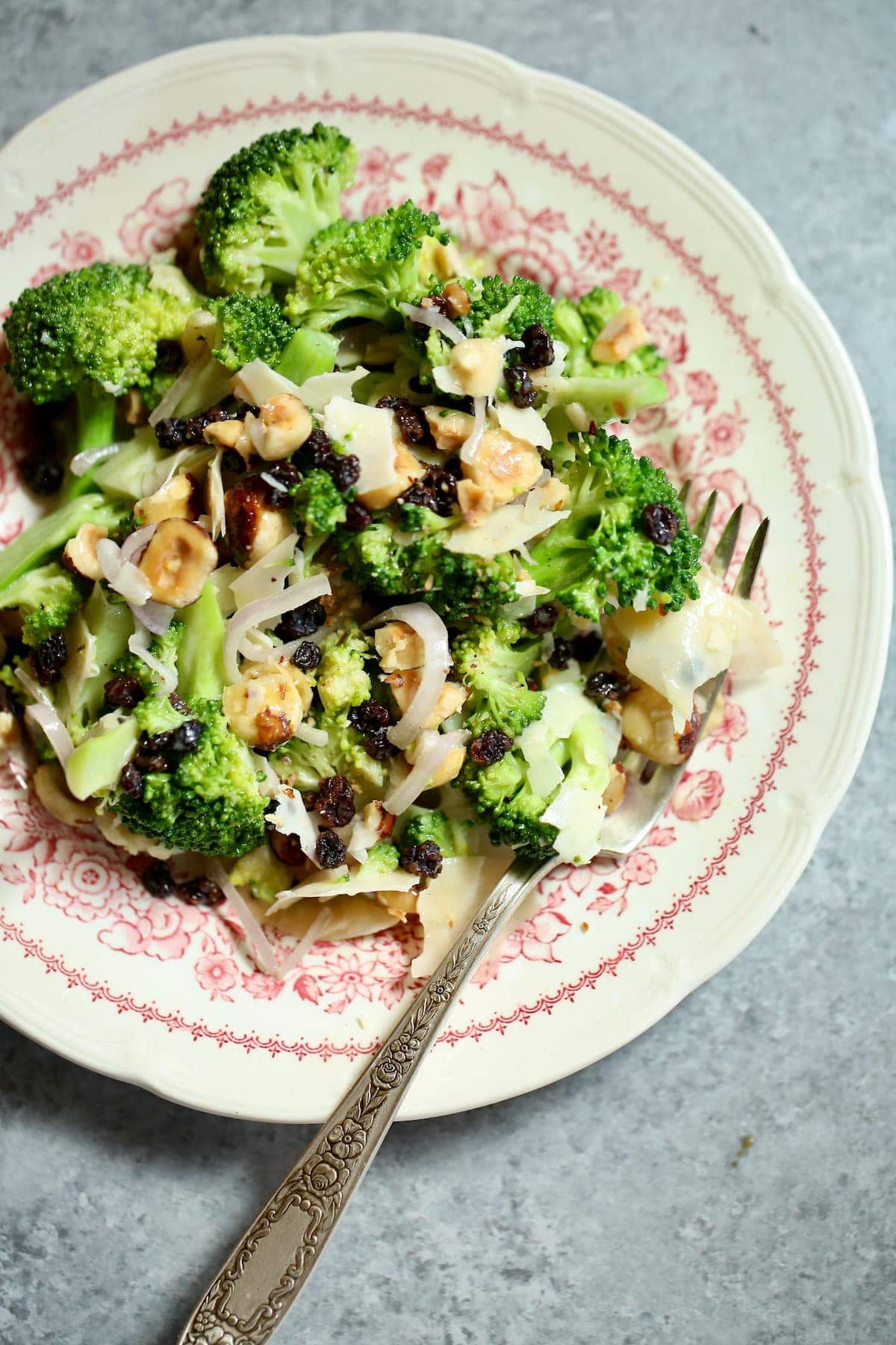 a small red and white plate with broccoli salad on it.