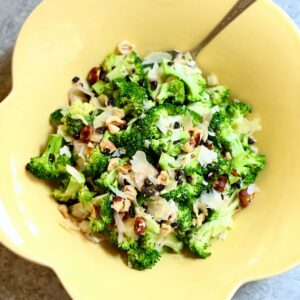 a fresh broccoli salad in a yellow bowl with a spoon.
