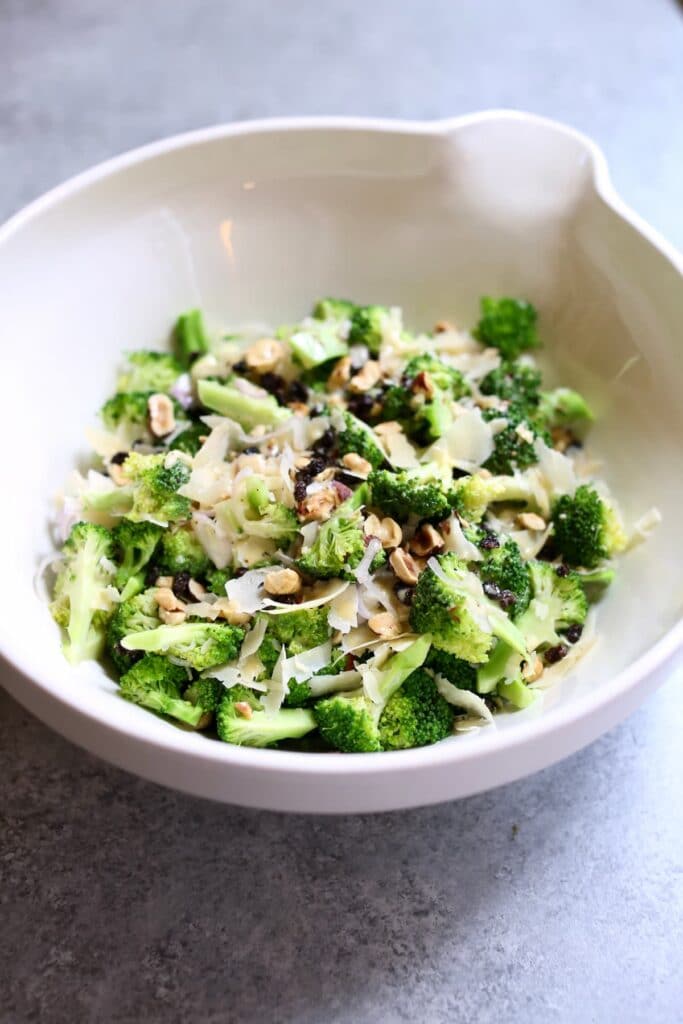 a white bowl with a side view of the broccoli salad inside.