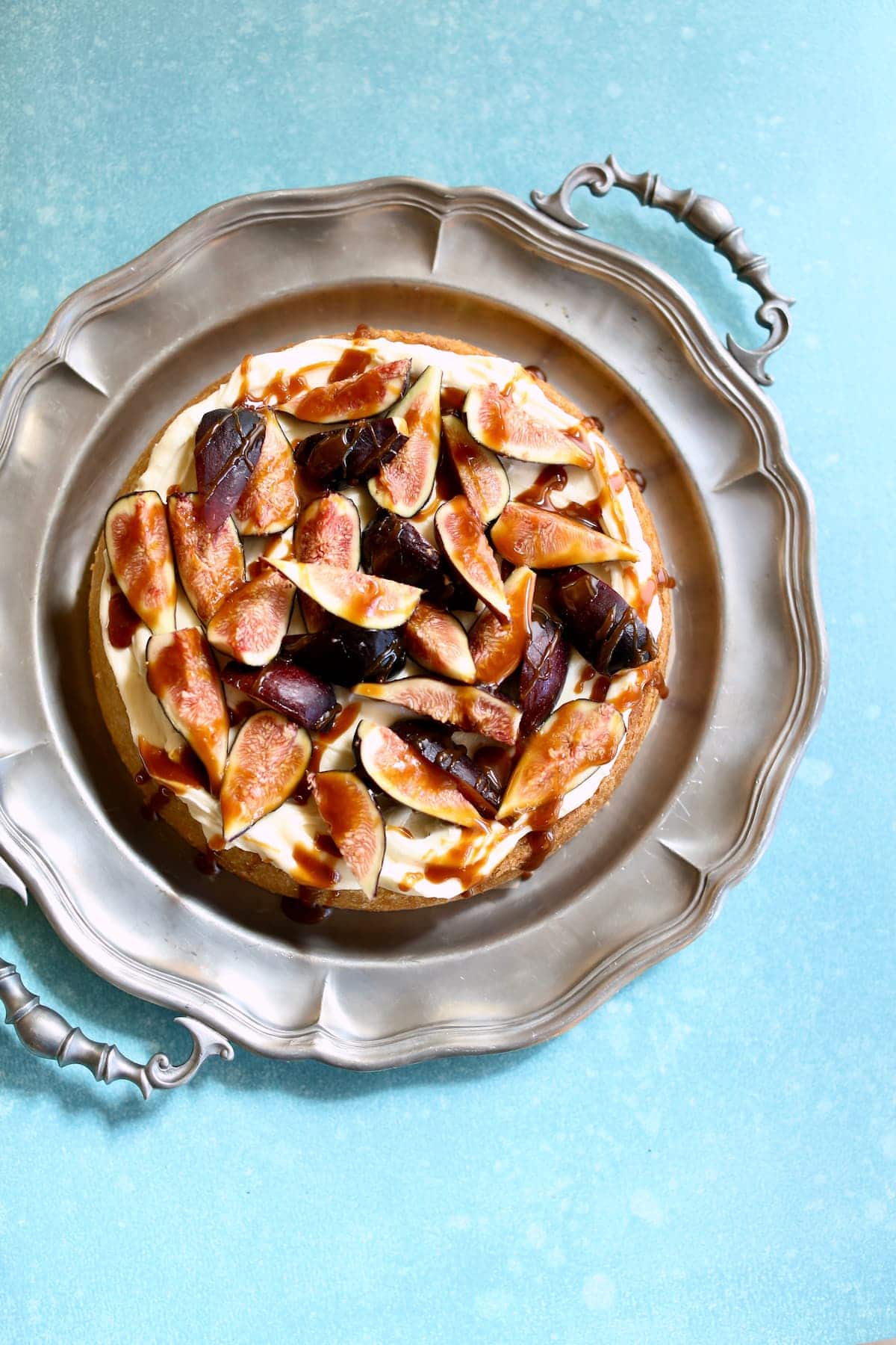 a cake with figs on it on a silver plate.