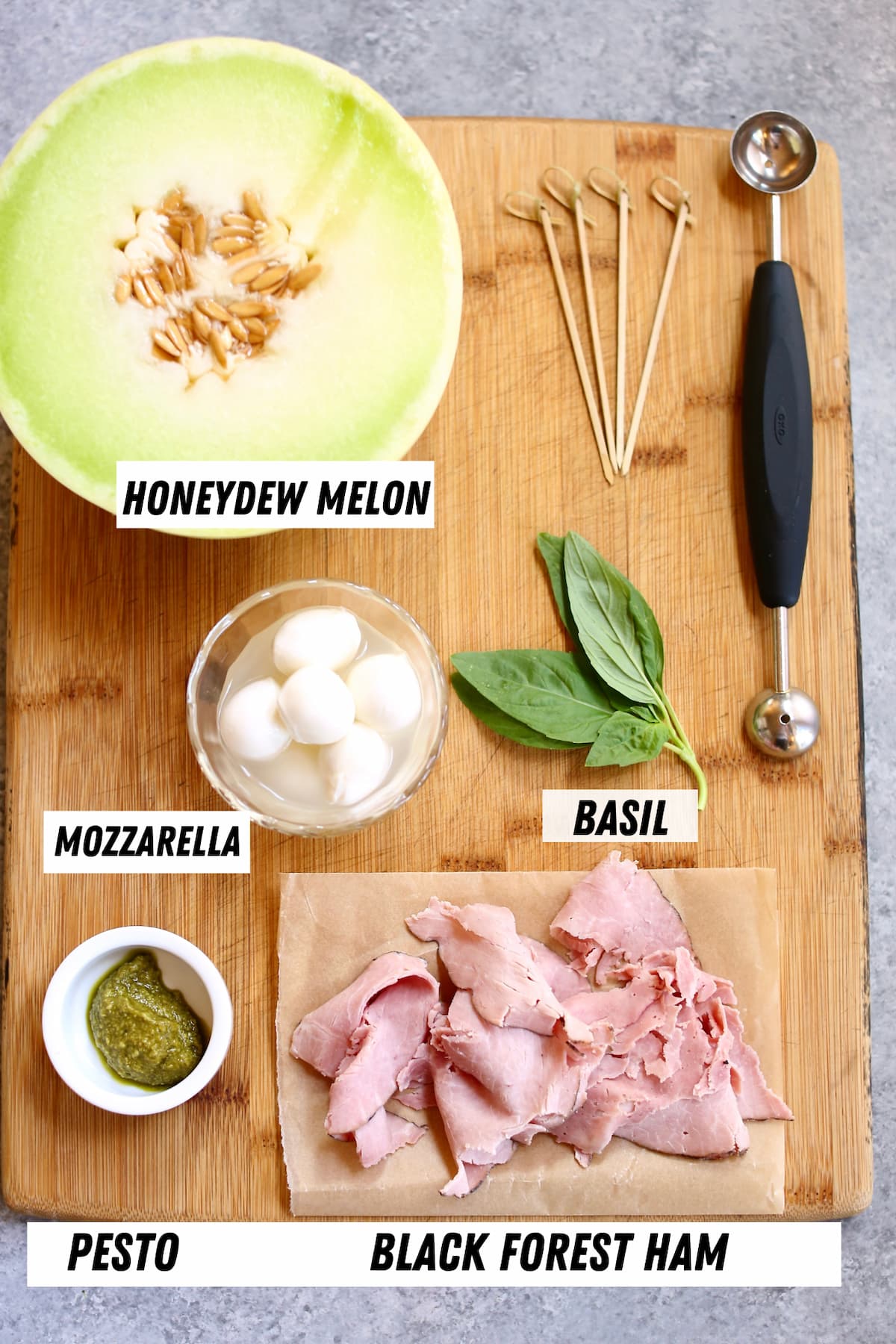 a board with ingredients on it, melon, ham and fresh mint and mozzarella cheese.