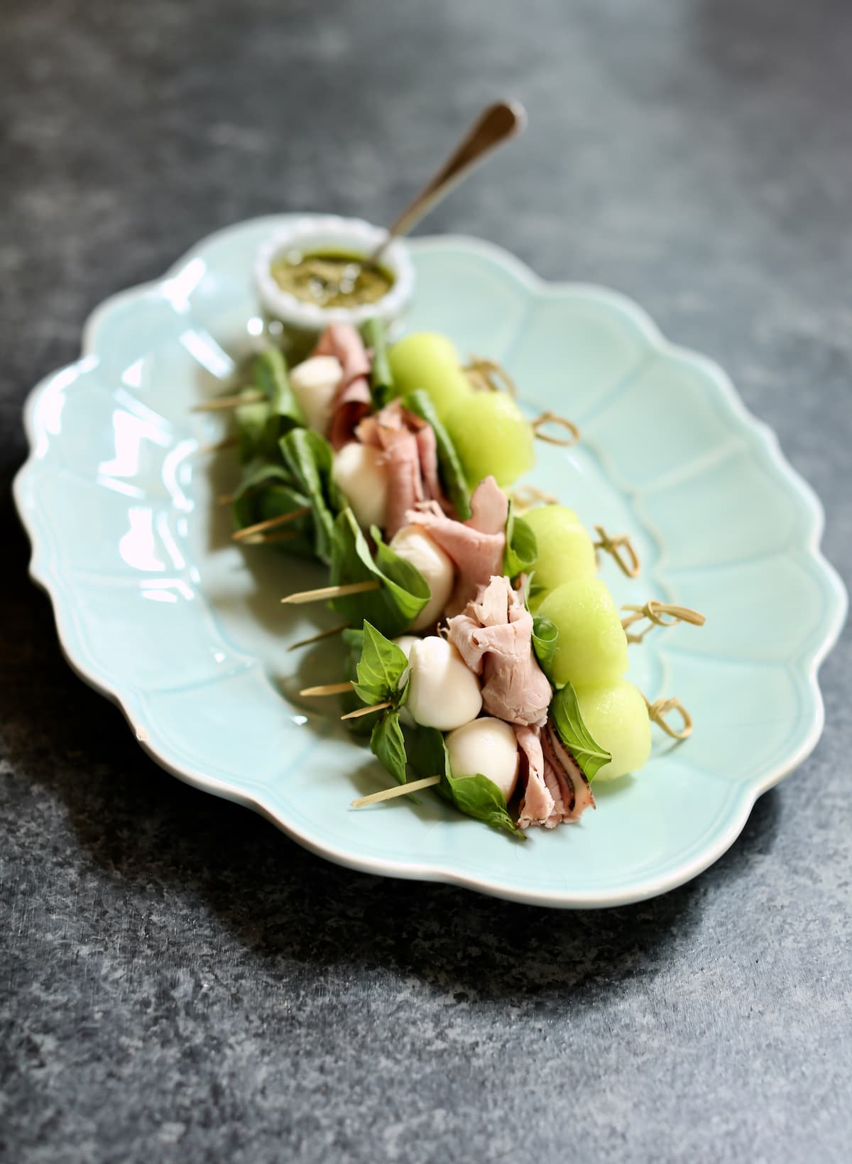 a small blue plate of melon skewers.