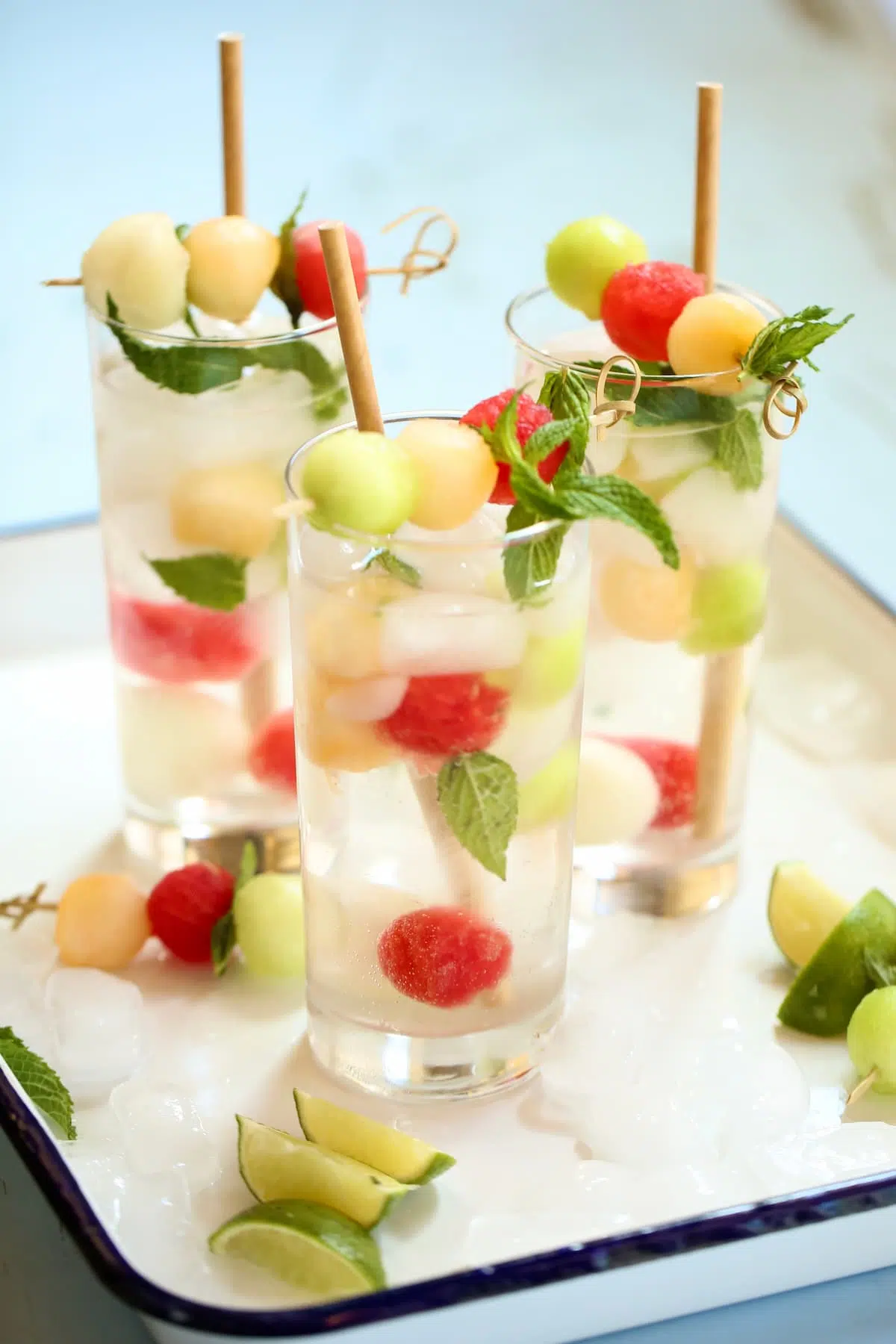 a white tray with several drinks with melon balls.
