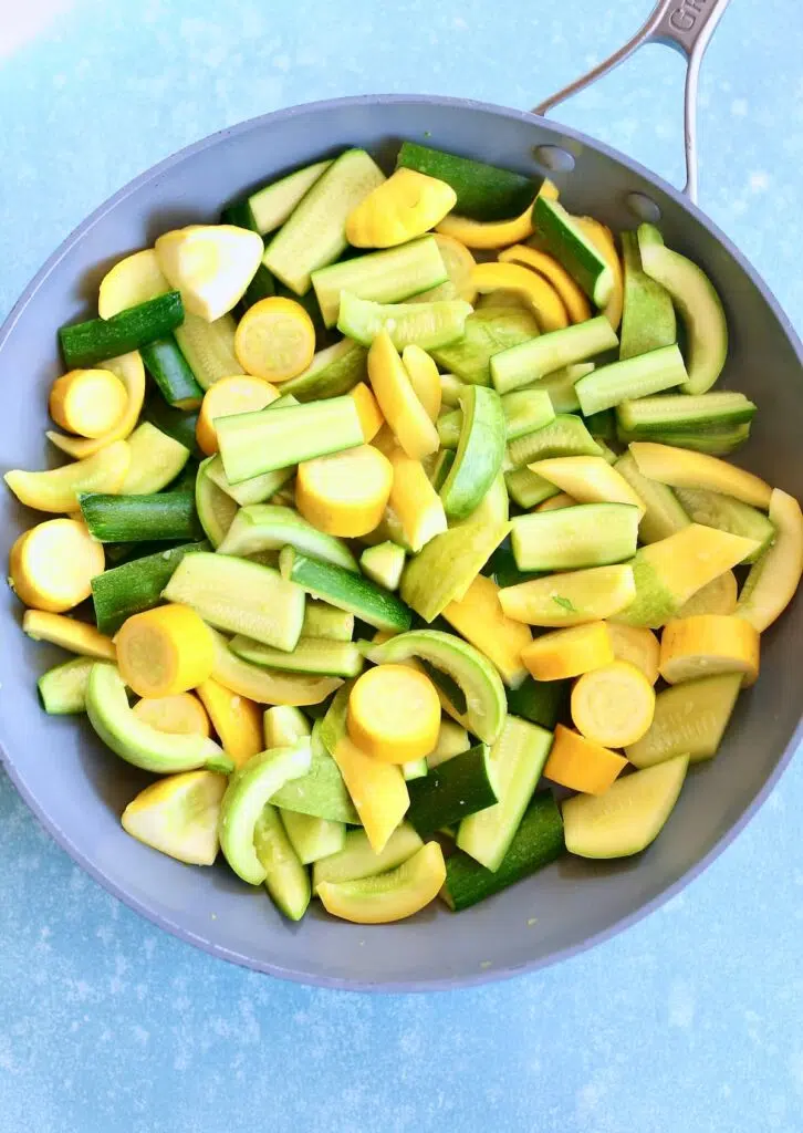 a gray skillet with cut zuchini in it.