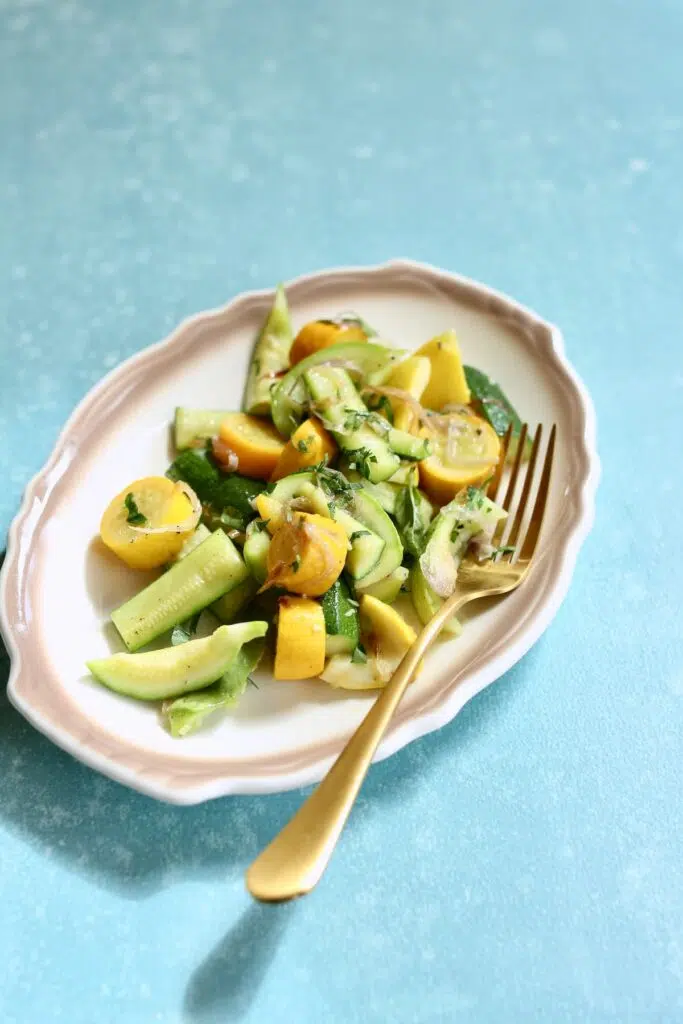 a white and tan plate of cooked zucchini.