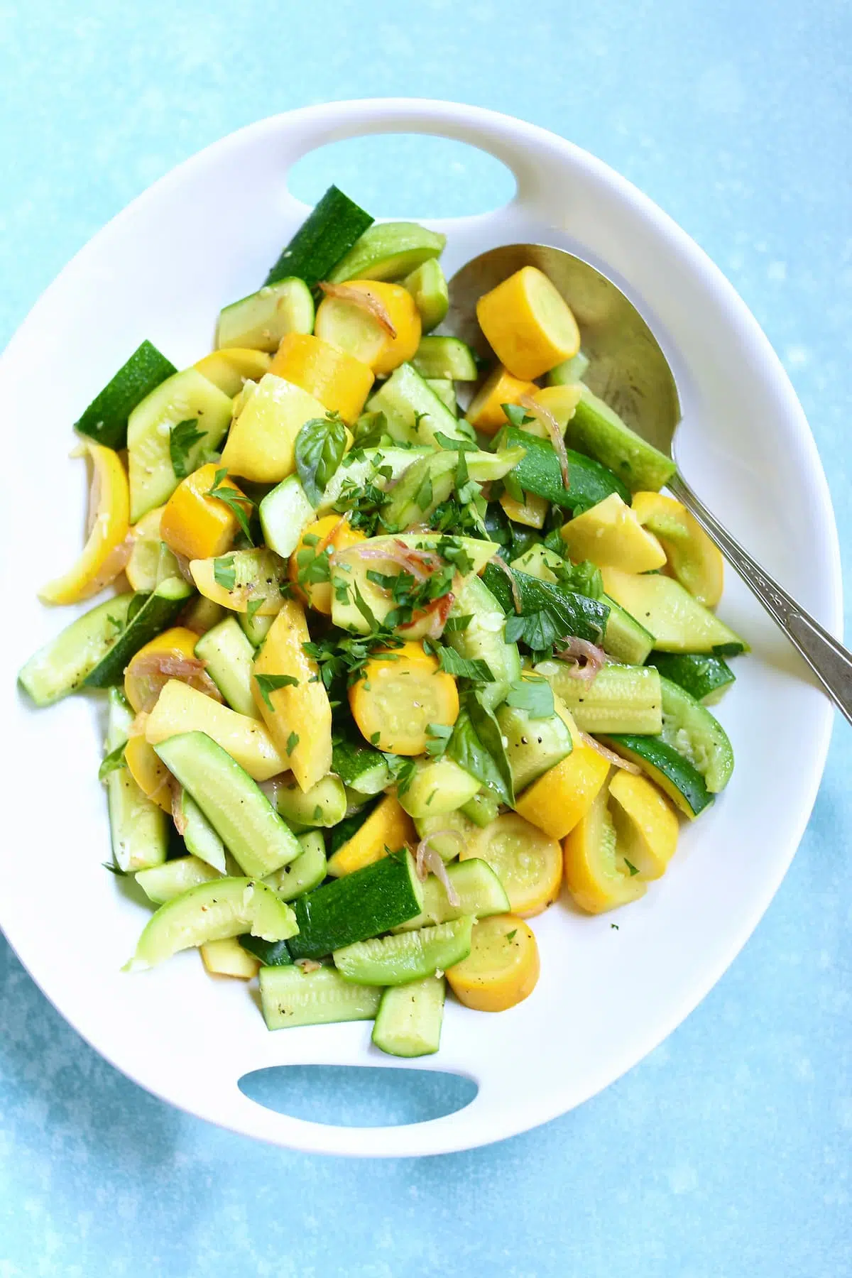 a white platter with assorted zucchini in it and a spoon.
