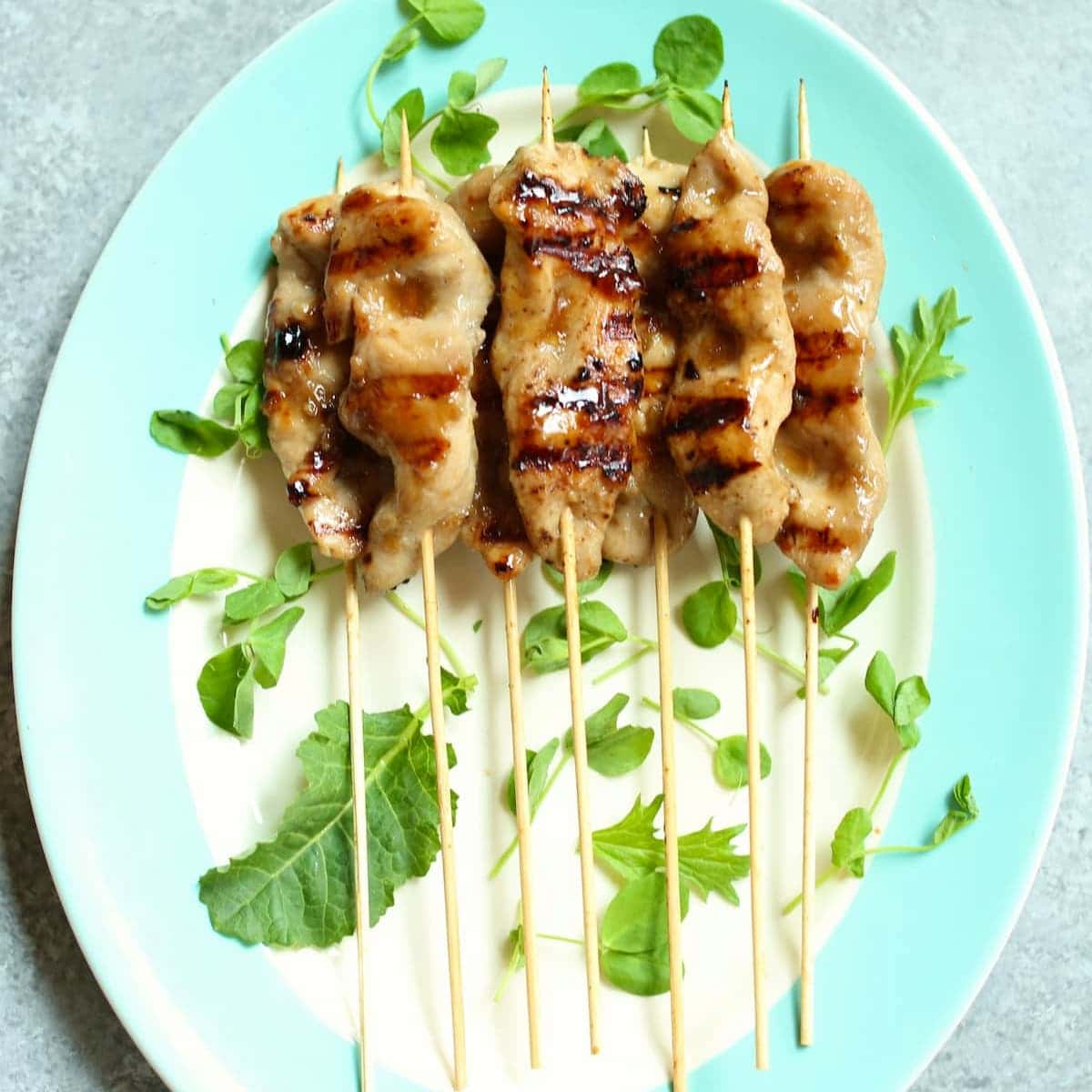 a square photo of teriyaki chicken kabobs on a stick.