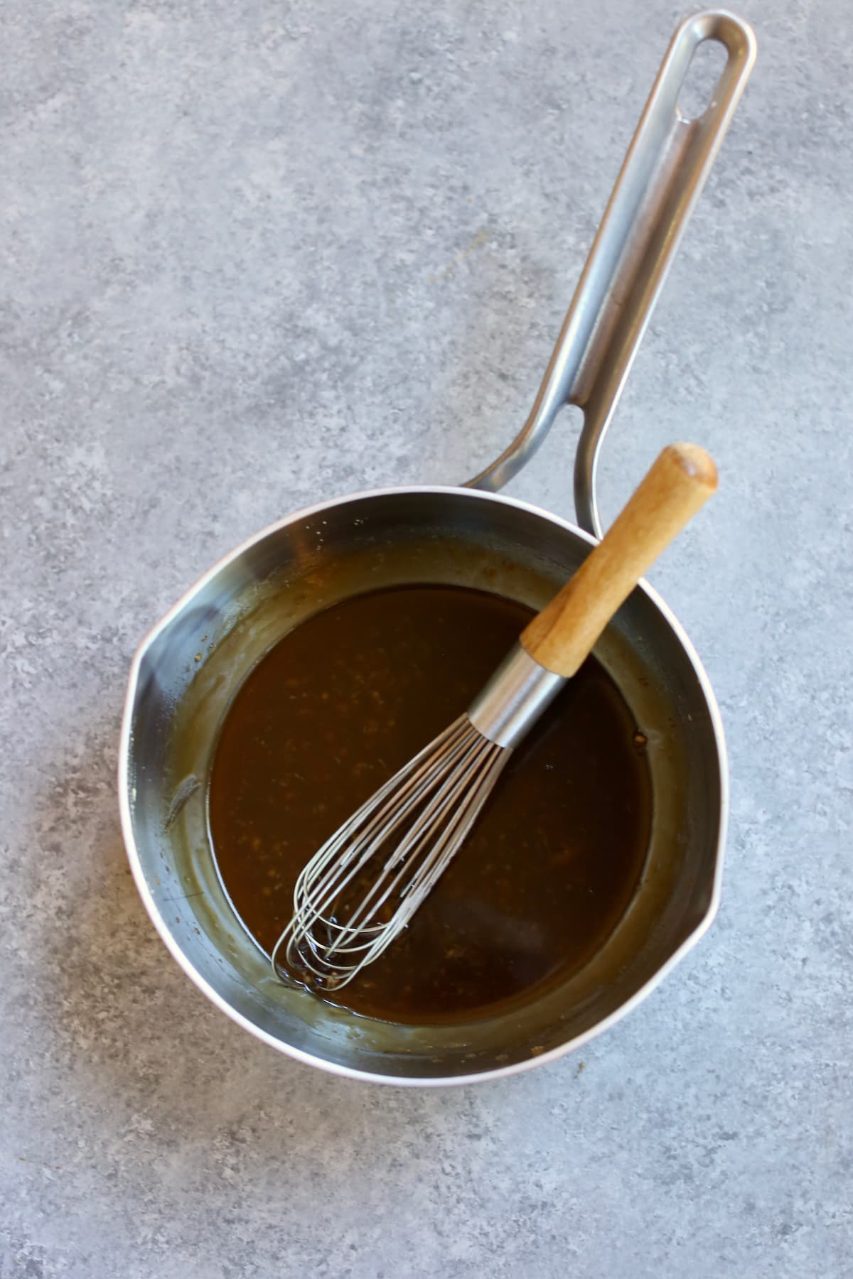 a sauce pan with a whisk and teriyaki sauce in it.  
