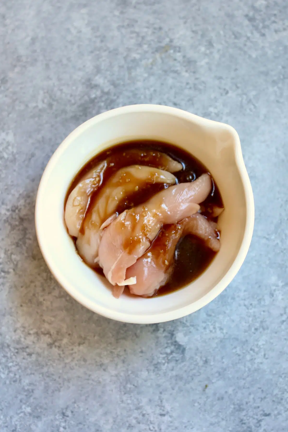 a bowl of chicken being marinated in teriyaki sauce.