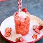 a strawberry drink on a white plate with ice and a text overlay saying the recipe name.