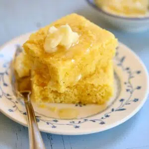 a close-up photo of cornbread and honey butter on a small plate.