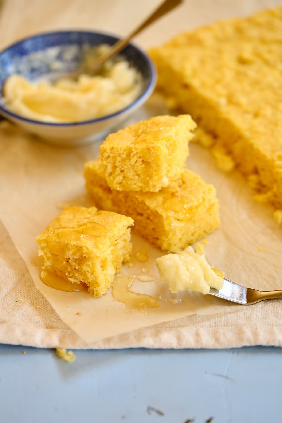 a stack of cornbread on a surface with a knife with butter on it.