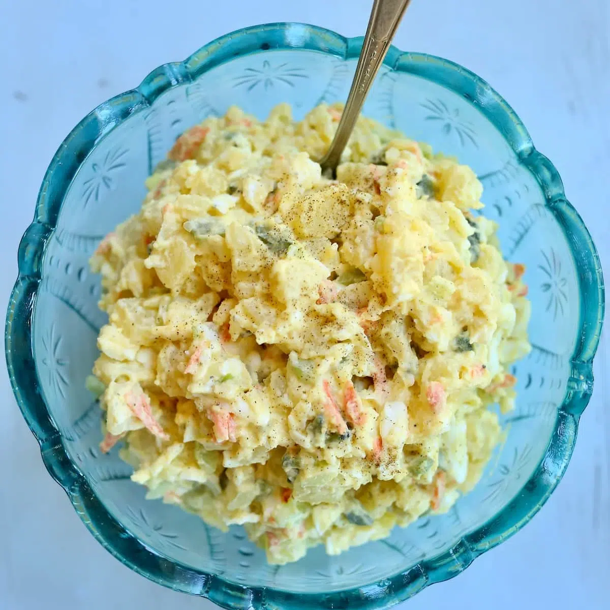 a blue bowl with potato salad in it.