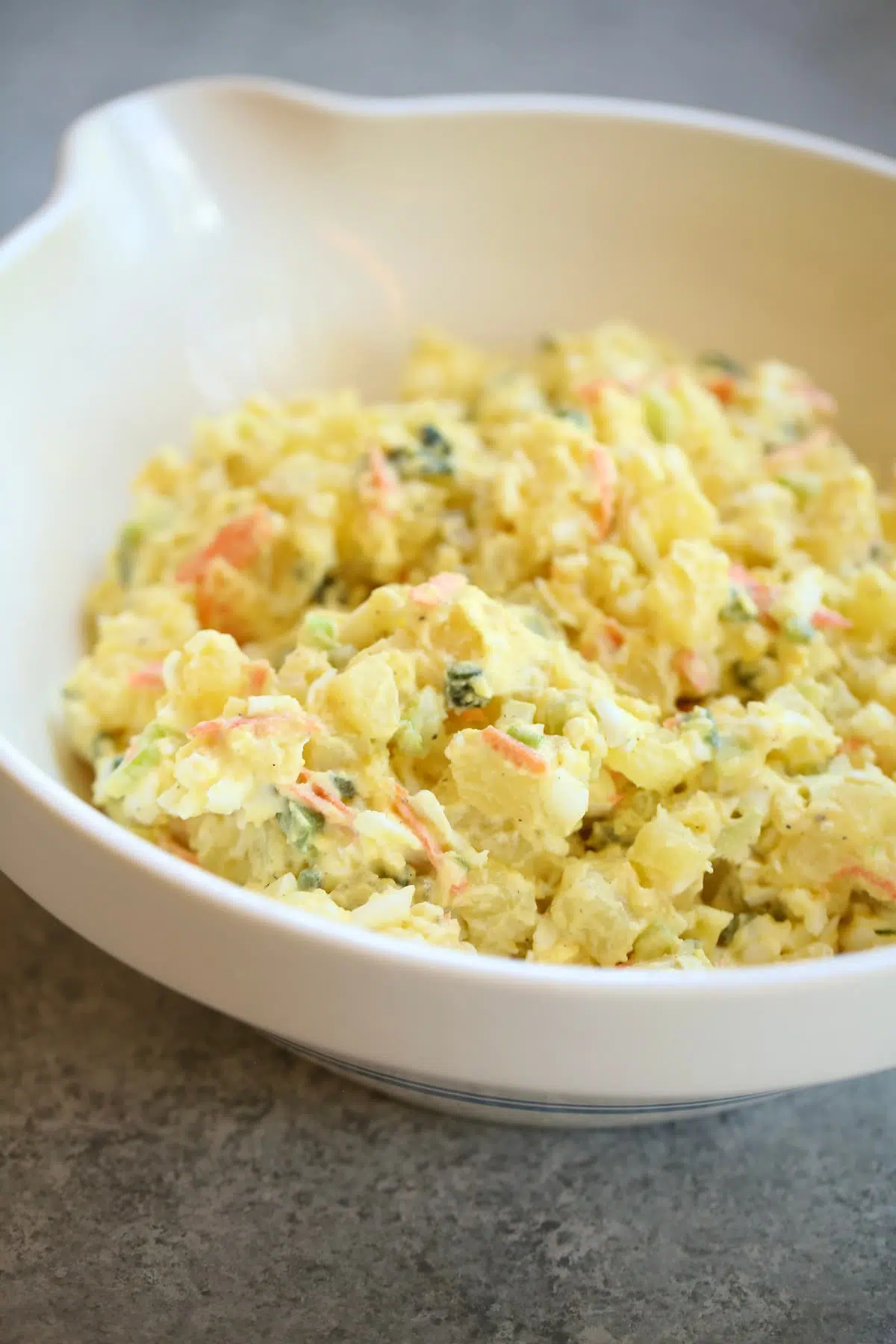 a white bowl with potato salad in it.