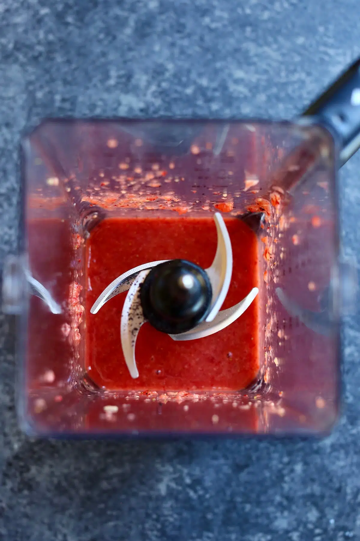 an overhead photo of a blender with strawberries in it.