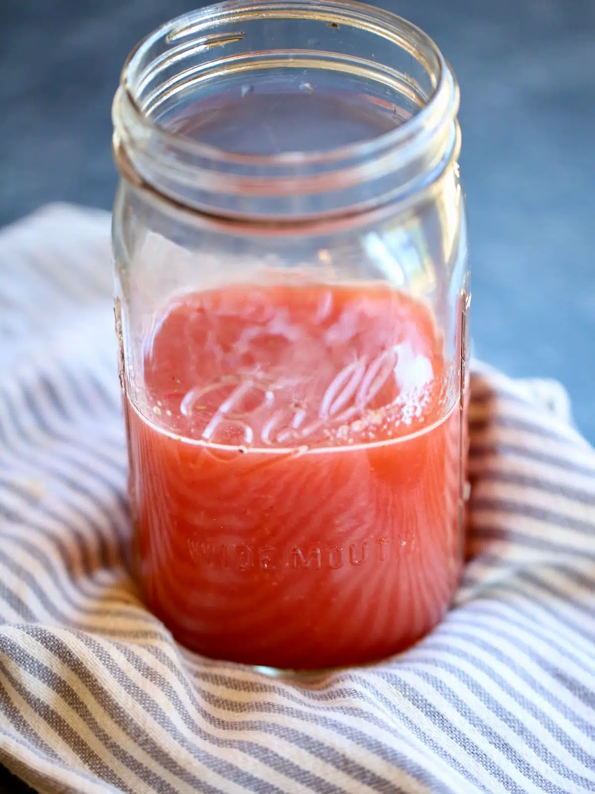 a mason jar of strawberry drink on a cloth.