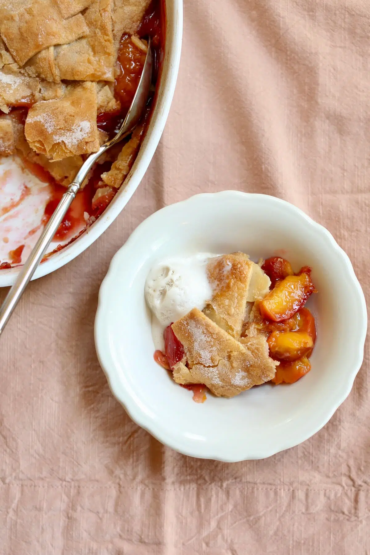 a small bowl of peach cobbler with more on the side.