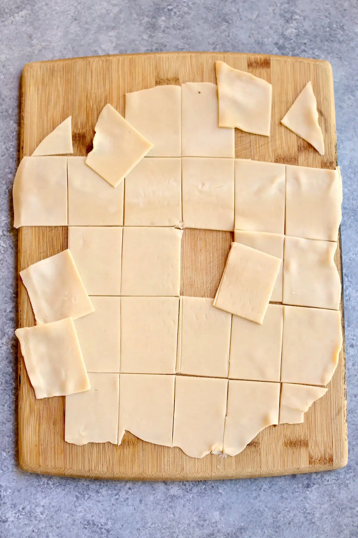 a cutting board with raw pie crust on it cut in squares.