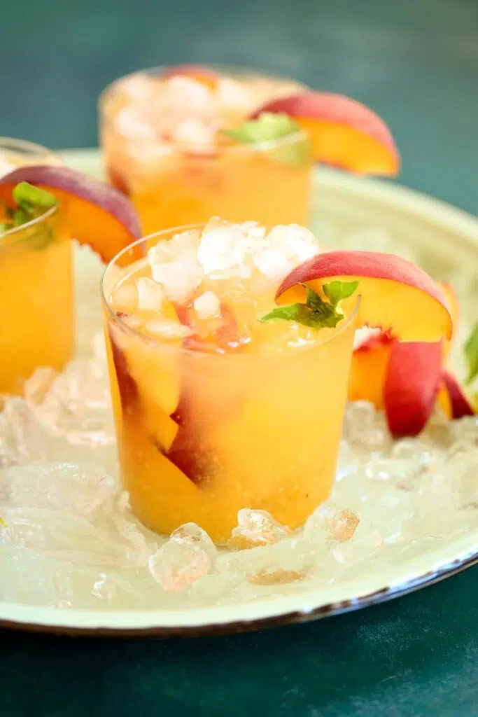 a peach drink on ice on a tray.