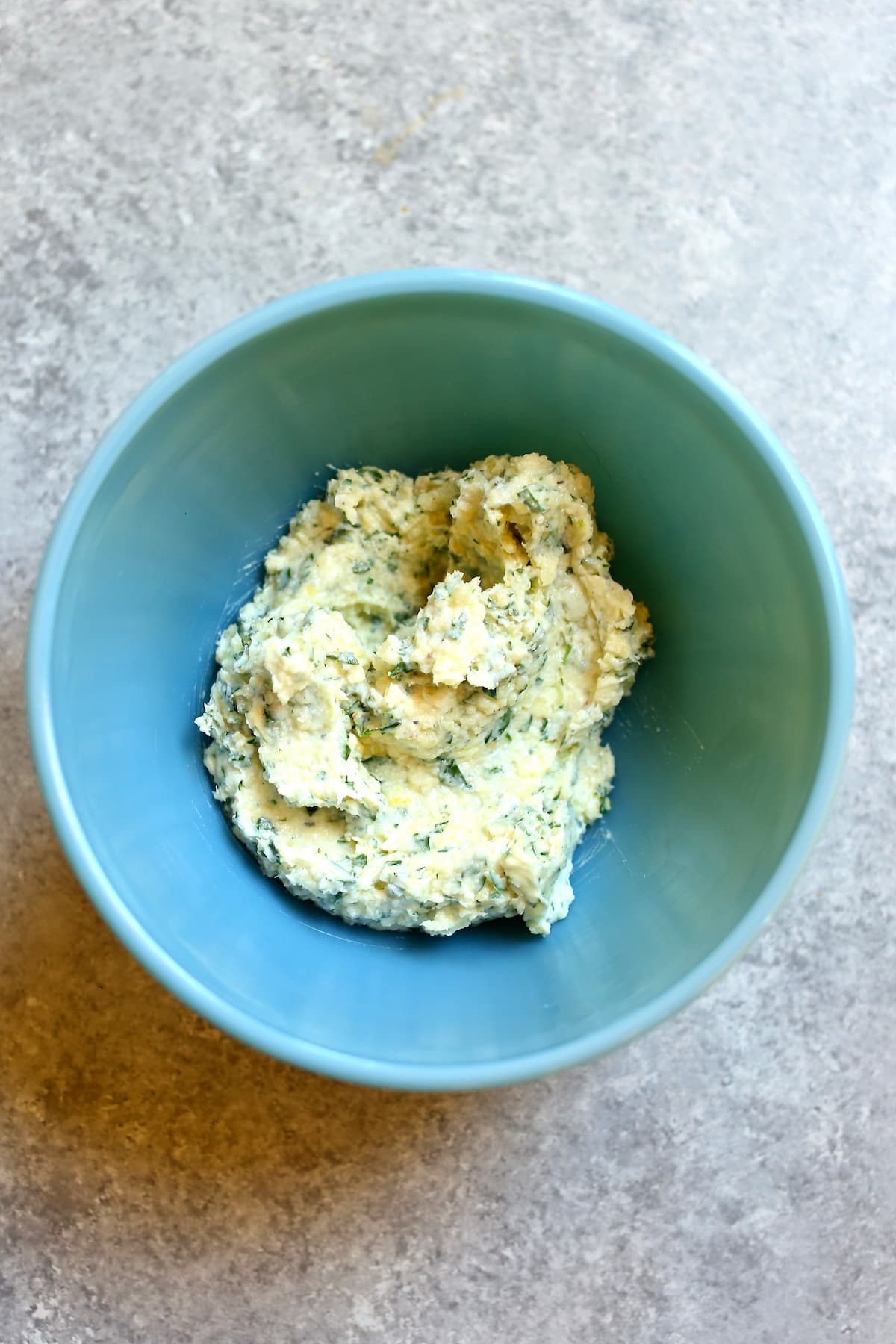 a blue bowl with garlic butter that's been mixed.