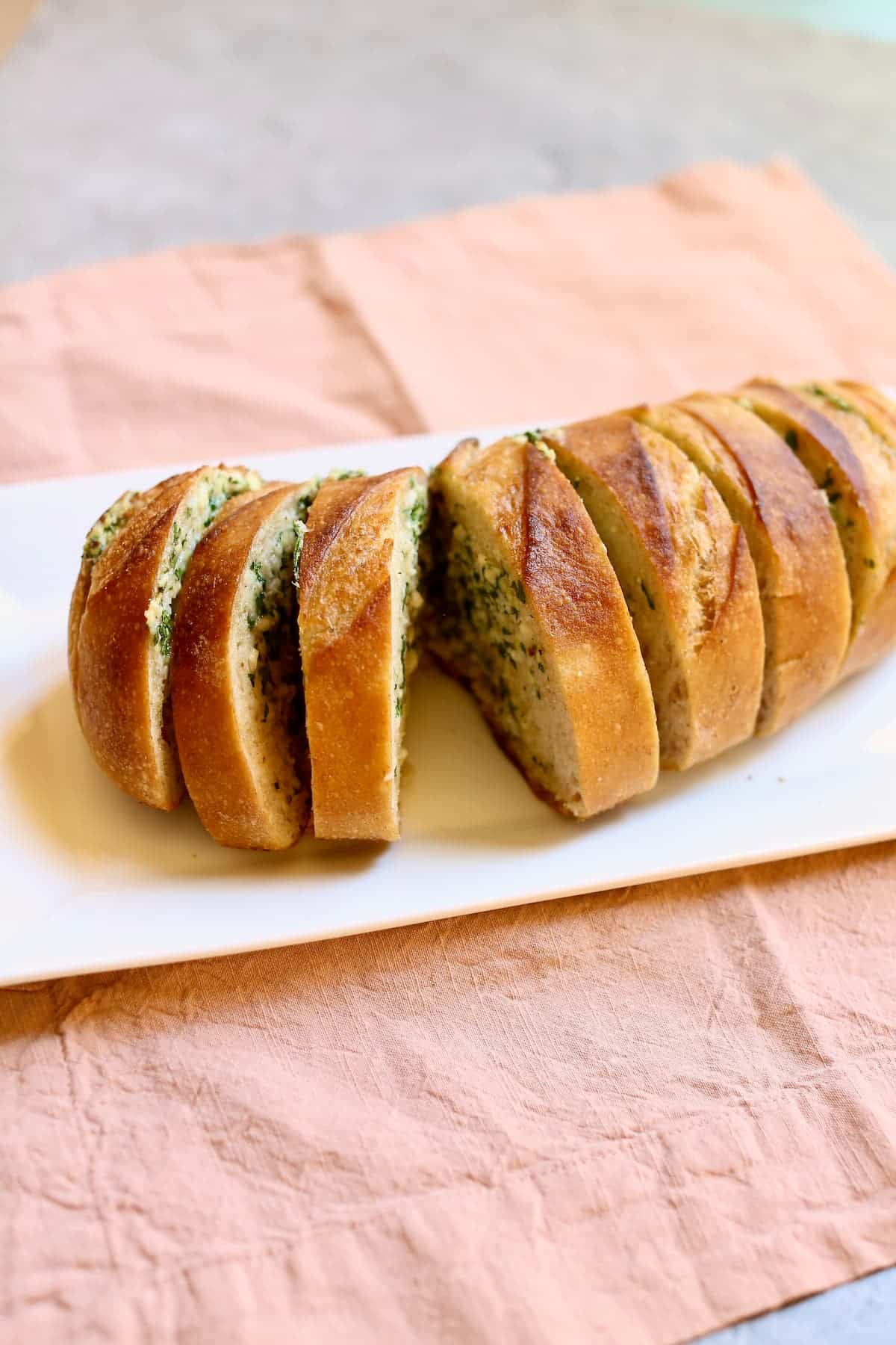 a loaf of garlic bread on a white tray.