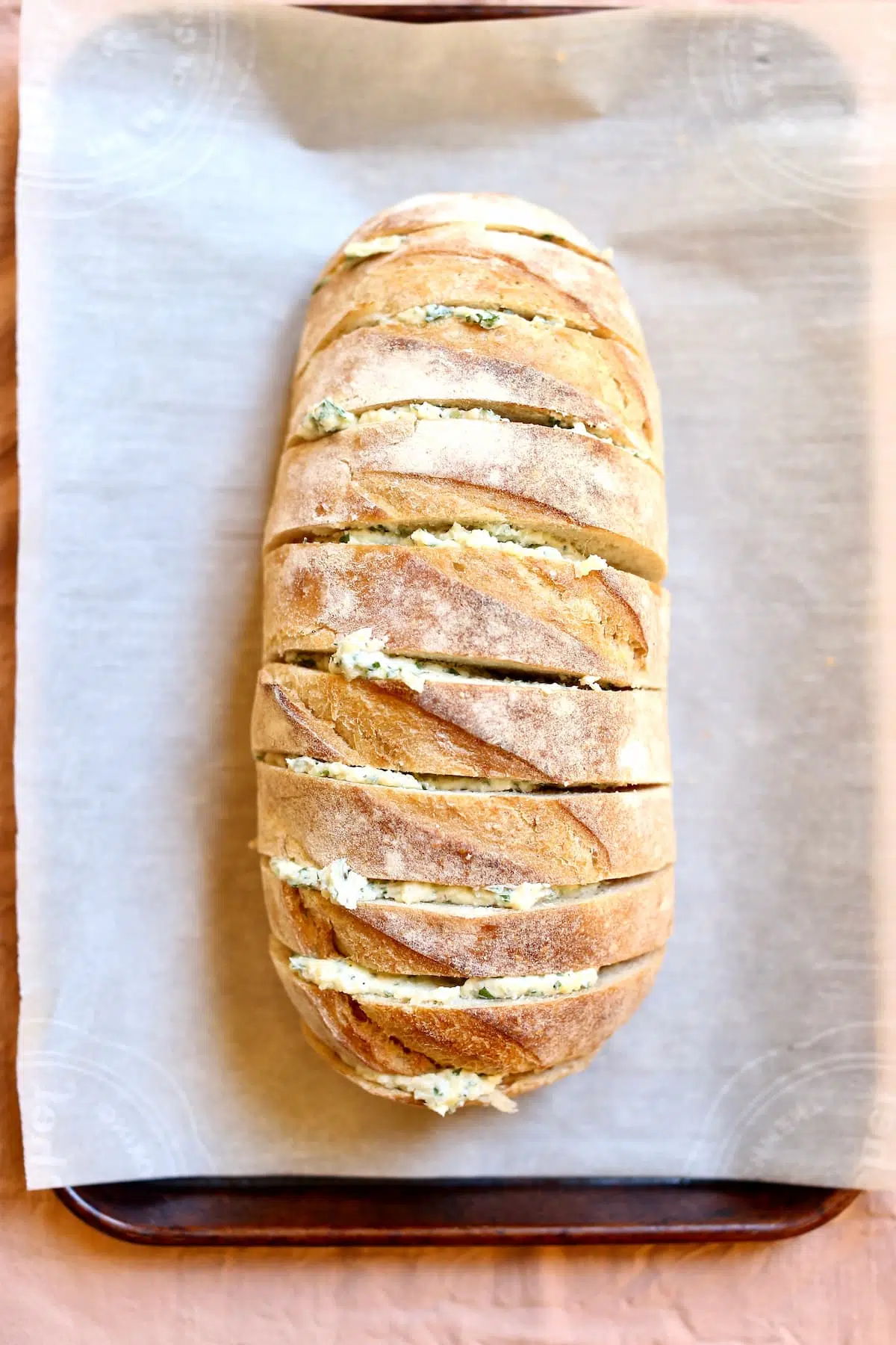 a loaf of garlic bread with butter in the slits.