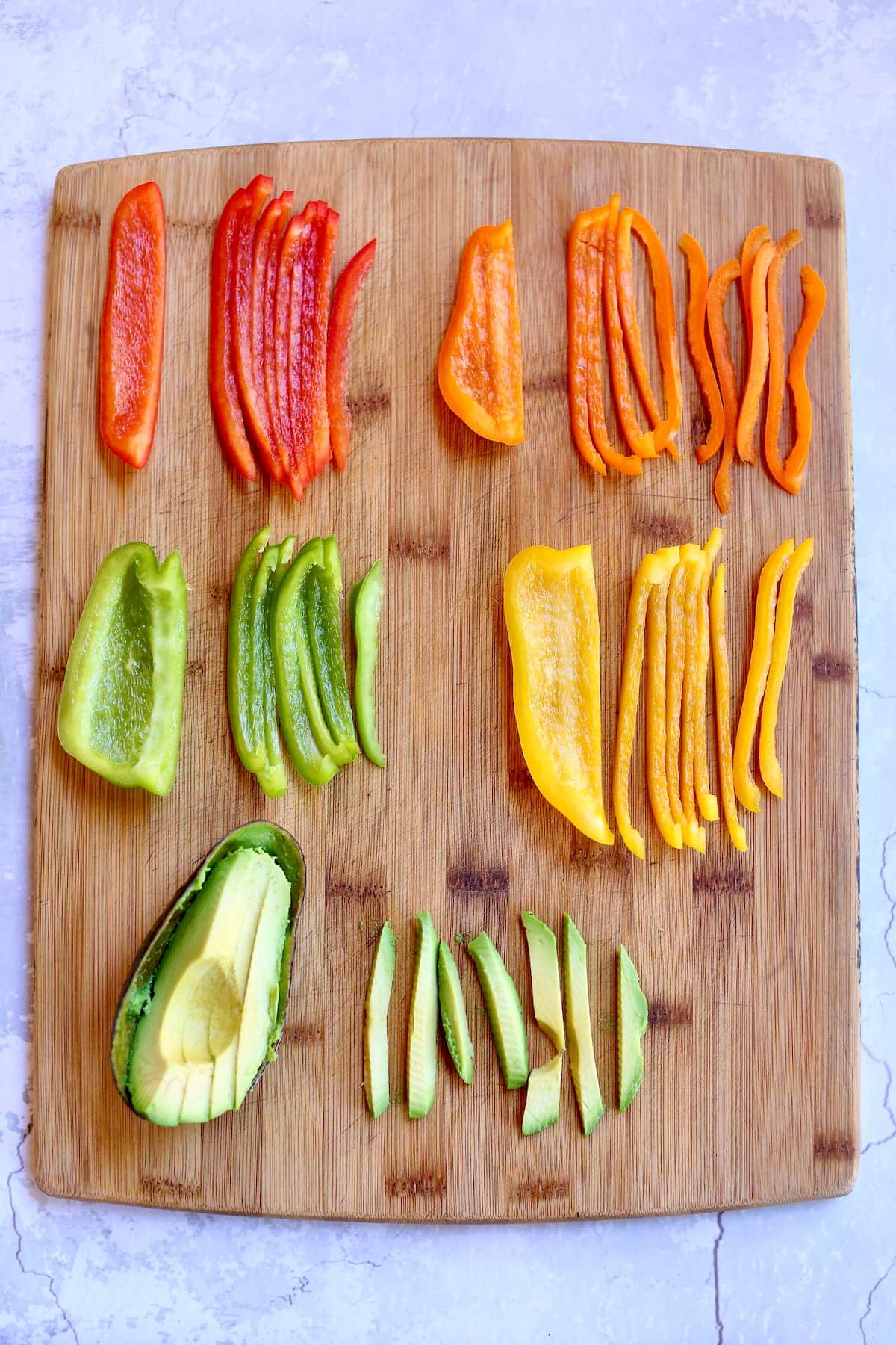 a cutting board with different colored peppers on it.