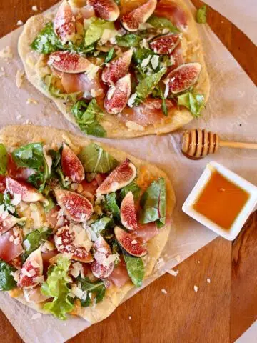 a close up photo of two fig pizzas.