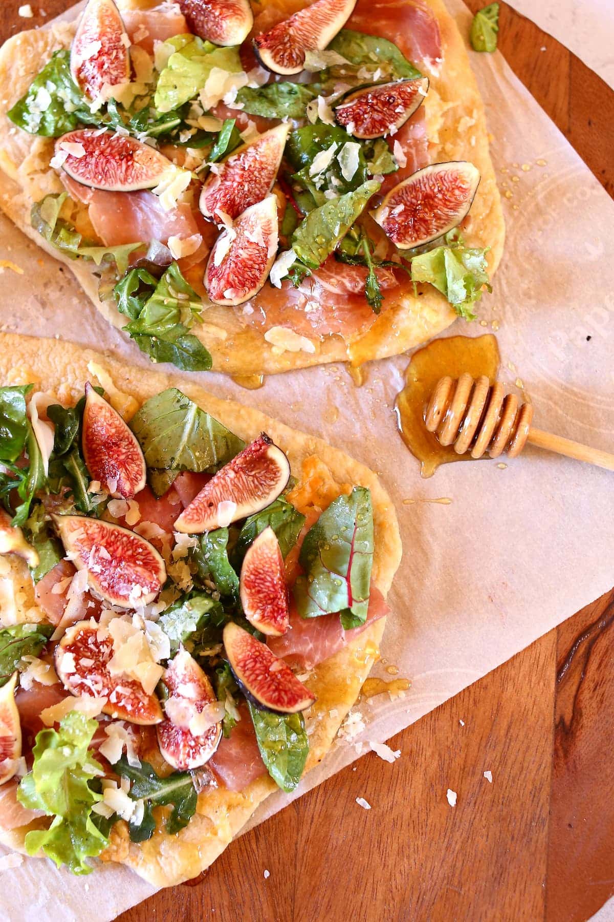 a close up photo of two fig pizzas on a baking sheet.