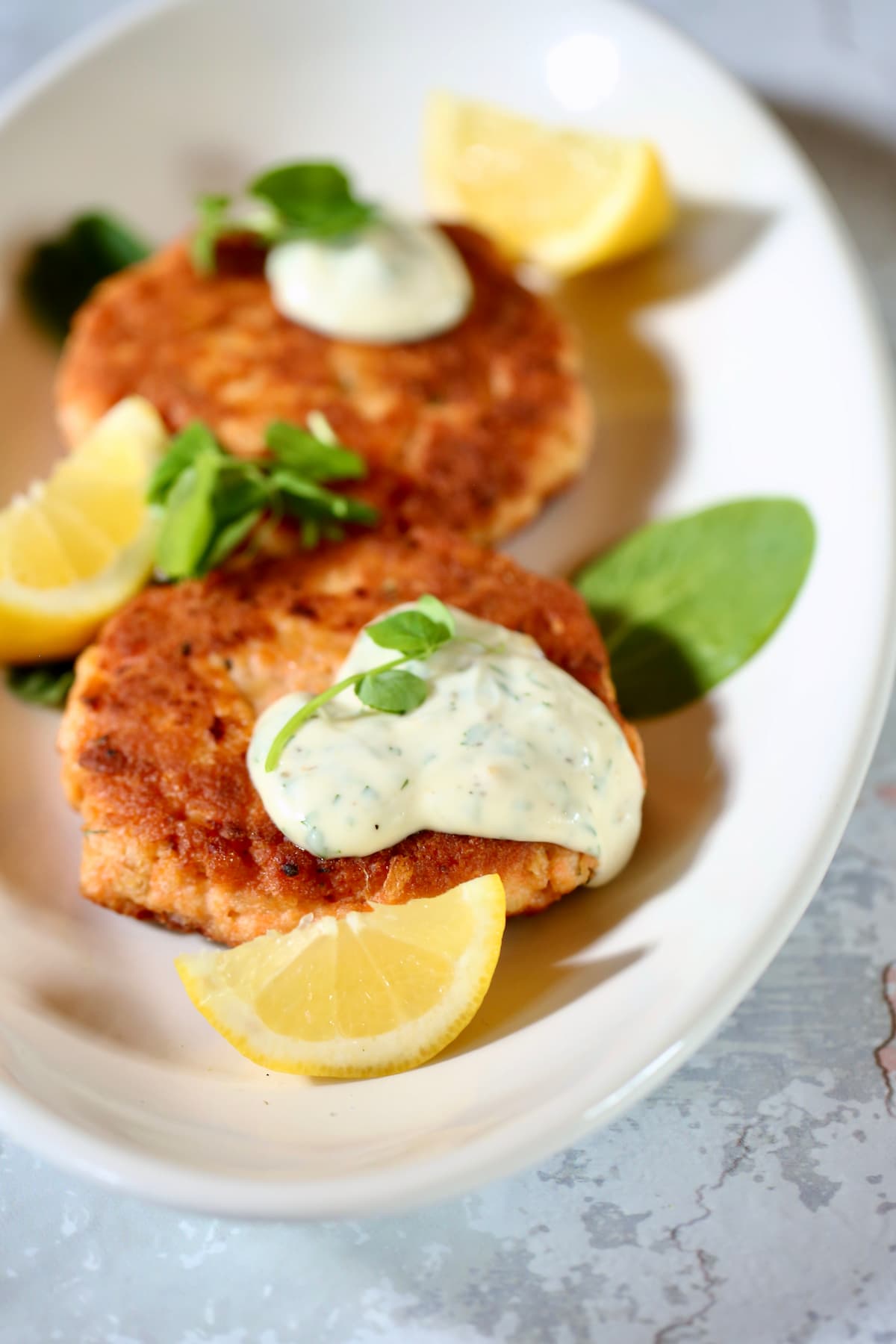 a close-up photo of salmon patties with fresh dill sauce.