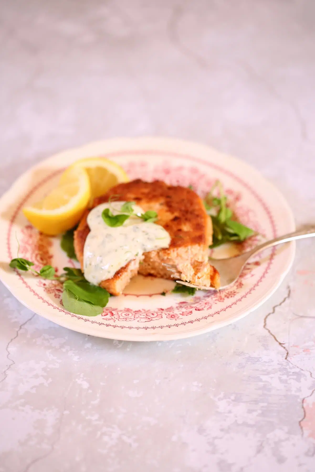a small plate with a salmon patty on it and fork.