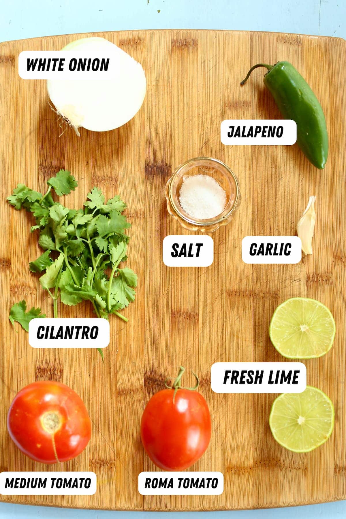 a wooden board with ingredients for salsa on it, labeled.