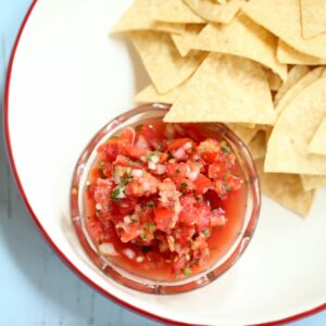 a square image of salsa and chips.