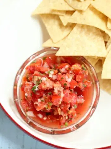 a square image of salsa and chips.