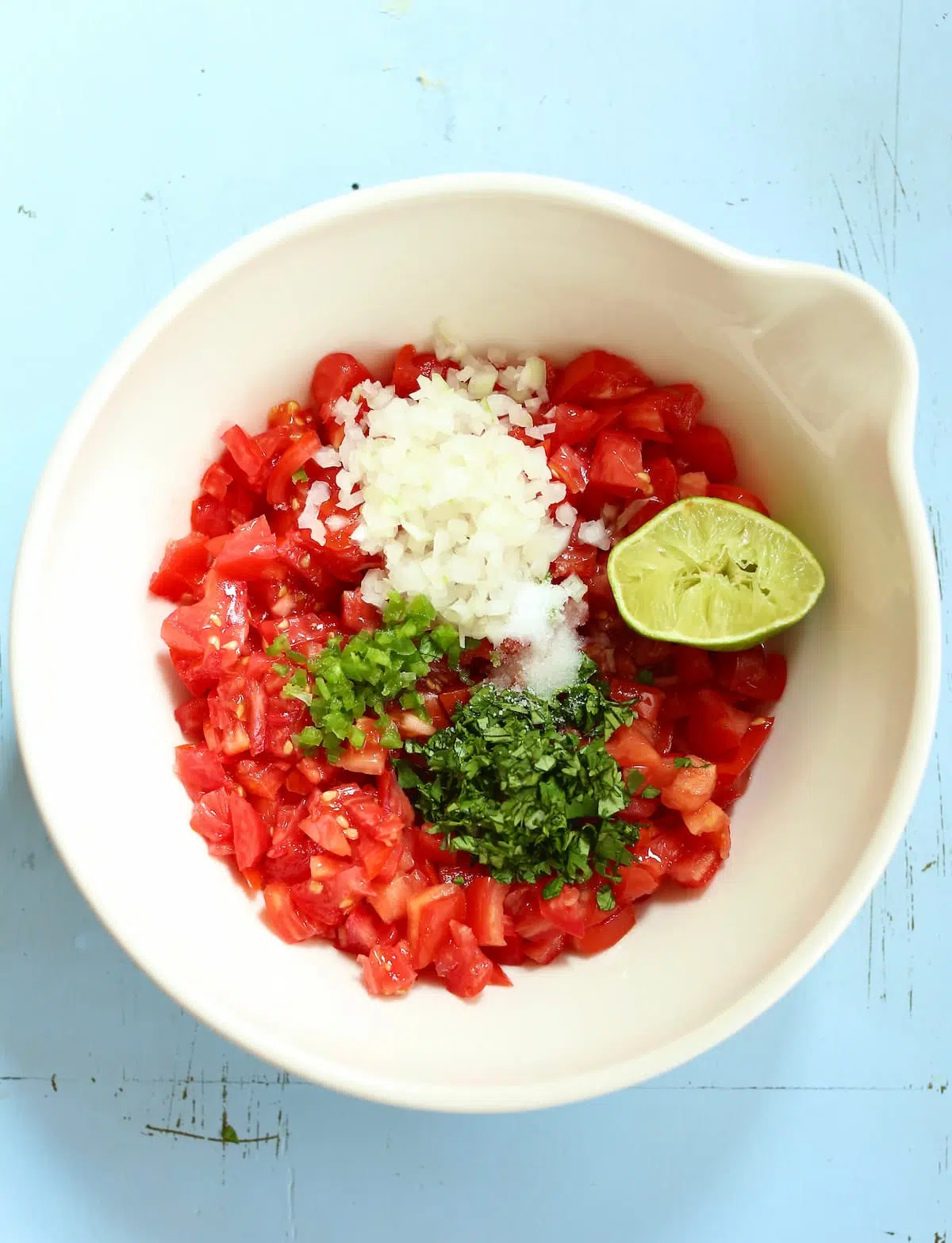 a white bowl of ingredients for salsa.